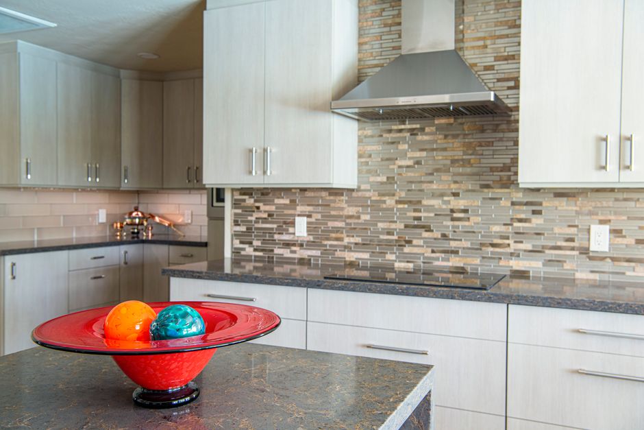 Kitchen with a granite countertop, white cabinets and a tiled backsplash.