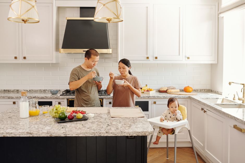 A bright kitchen with a stone countertop and a high chair beside the table.